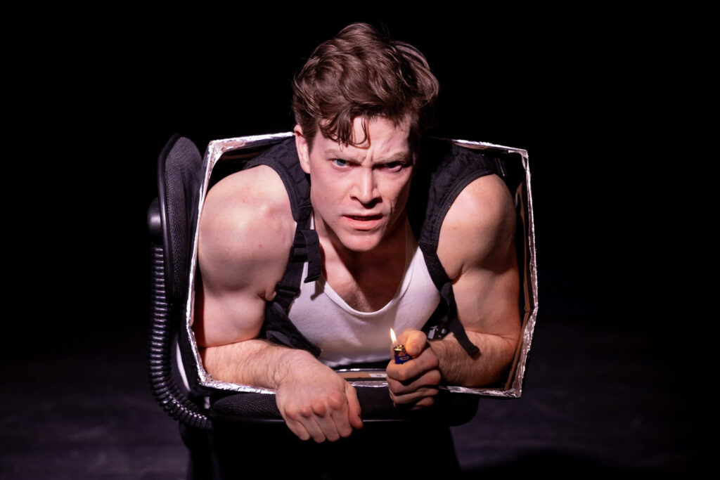 Intense male performer emerging from a theatrical prop, showcasing stagecraft, acting, and performance art for entertainment and theater productions.