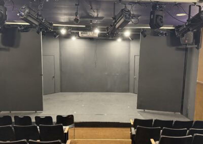 Black theater stage with professional lighting and sound equipment, ideal for live performances, comedy shows, and theater productions at The StageCrafts.