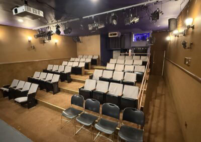 Underneath the stage theater seating with tiered chairs and a small stage, ideal for live performances, comedy shows, and theater events at The StageCrafts.