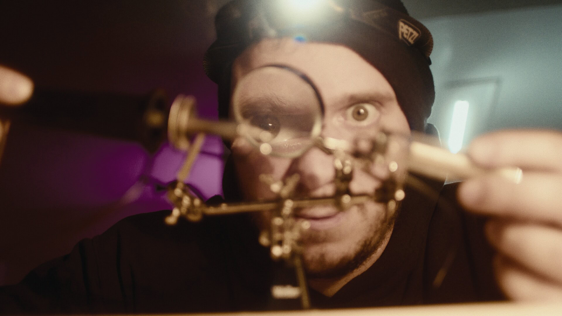 Microbiologist with safety goggles examining a scientific contraption in a laboratory.